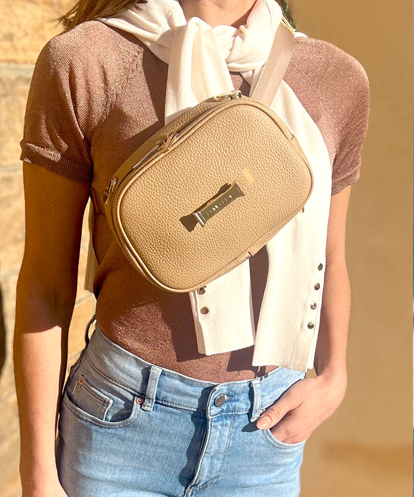 Person wearing a crème caramel AVAIA Petit as a crossbody bag with a neutral background
