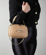 Load image into Gallery viewer, Person holding a crème caramel AVAIA Petit bag, using a handheld strap with a short gold chain strap.