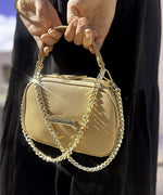 Load image into Gallery viewer, A close up of a crème caramel AVAIA Petit bag being held using a padded chain strap.