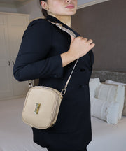Person wearing a crème caramel AVAIA Petit as a shoulder bag, using a fabric strap.