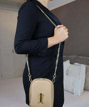 The AVAIA Petit bag in vertical position, over the shoulder with a gold chain strap.