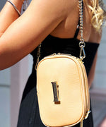 Load image into Gallery viewer, Person wearing a crème caramel AVAIA Petit bag as a shoulder bag, using a gold chain strap.