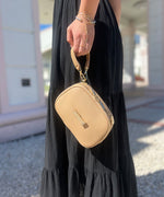 Load image into Gallery viewer, A person holding a crème caramel AVAIA Petit bag using the handheld strap in the wristlet style.