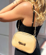 Load image into Gallery viewer, Person wearing a crème caramel AVAIA Petit bag as a shoulder bag, using a gold chain strap.
