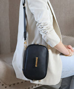 Load image into Gallery viewer, A person wearing a noir AVAIA Petit as a shoulder bag, using the black fabric strap, sat down.