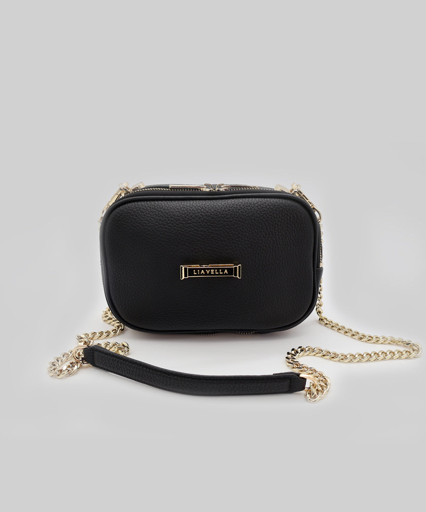 A AVAIA Petit noir, with the padded gold chain strap attached, on a white studio background.