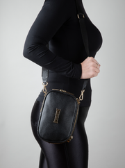 Person wearing a noir AVAIA Petit as as a shoulder bag, using a fabric strap, in a studio.