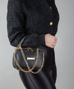 Load image into Gallery viewer, Person holding an AVAIA Petit in noir using a padded chain strap.