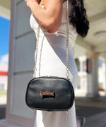 Load image into Gallery viewer, A person wearing an AVAIA Petit in noir as a shoulder bag, using a long padded chain strap.