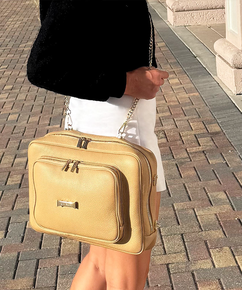 Person wearing a crème caramel AVAIA as a crossbody bag, using a gold chain strap.