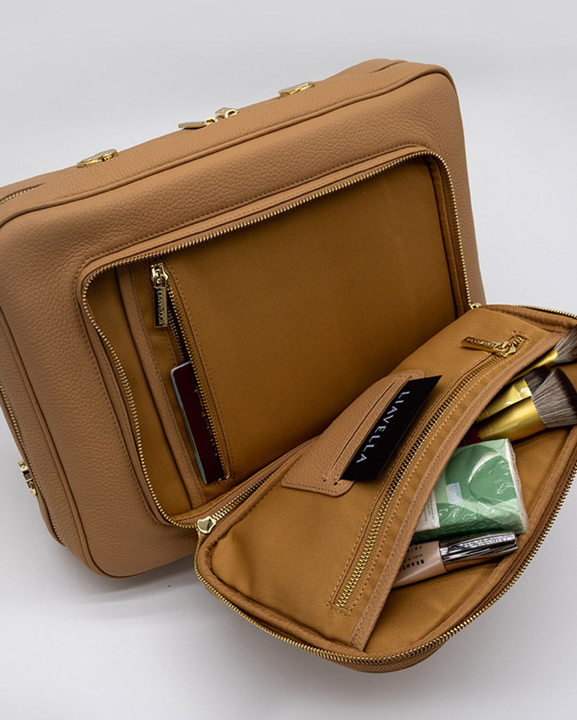 The crème caramel AVAIA bag with makeup items on a white background