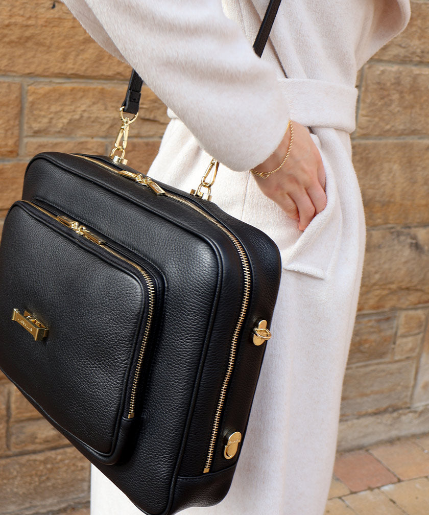 Action shot of a person wearing an AVAIA Noir bag as a shoulder bag, using a long leather strap.