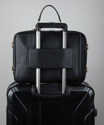 Load image into Gallery viewer, Noir AVAIA bag, using the luggage pass through strap, placed on a black suitcase.