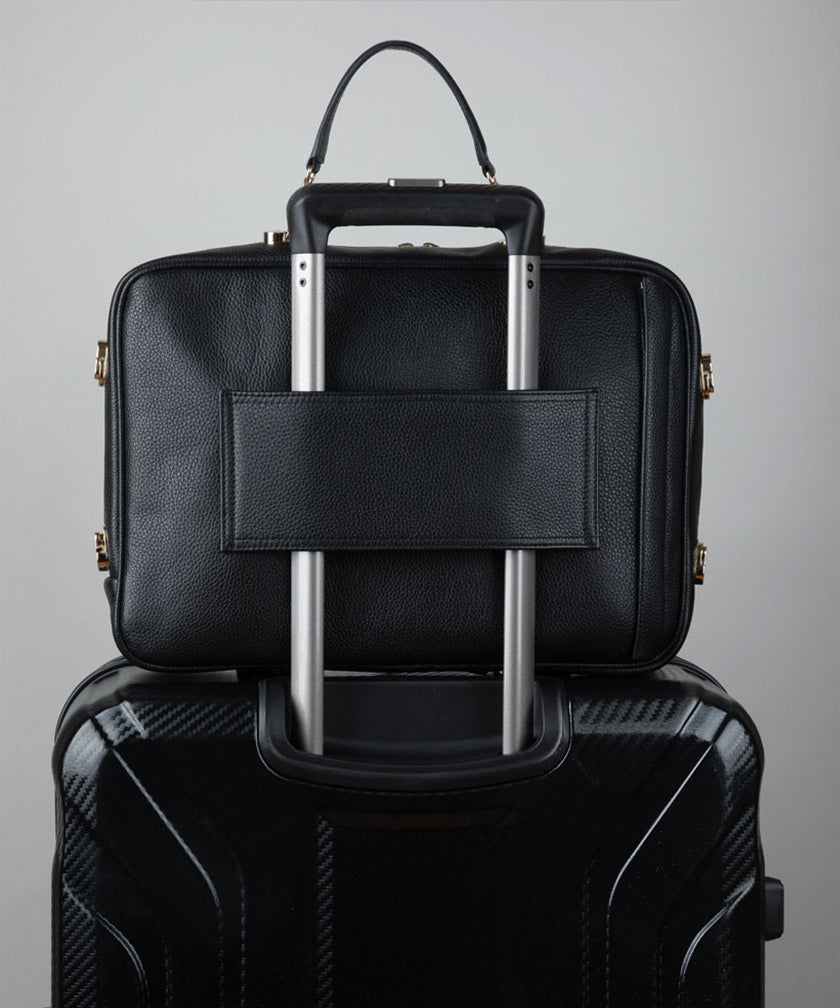 Noir AVAIA bag, using the luggage pass through strap, placed on a black suitcase.