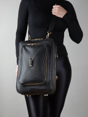 A person wearing a noir AVAIA as a crossbody bag, using a fabric strap.