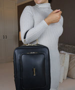 Load image into Gallery viewer, Woman holding the AVAIA bag using the handheld leather strap, she is indoors.