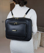 Load image into Gallery viewer, A woman wearing the AVAIA bag as a horizontal backpack, she is wearing a grey ribbed sweater indoors.
