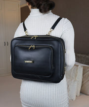 A woman wearing the AVAIA bag as a horizontal backpack, she is wearing a grey ribbed sweater indoors.