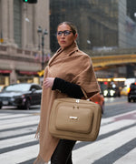 Load image into Gallery viewer, Woman holding the AVAIA Crème Caramel handbag on a city street