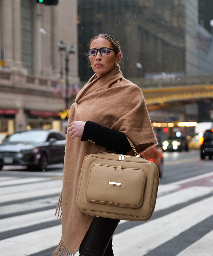 Woman holding the AVAIA Crème Caramel handbag on a city street
