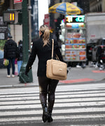 Load image into Gallery viewer, Person walking with the AVAIA Crème Caramel as a shoulder bag, on a city street