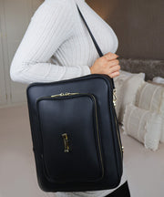 Woman wearing the AVAIA bag over the shoulder, showing the gold hardware and zips.