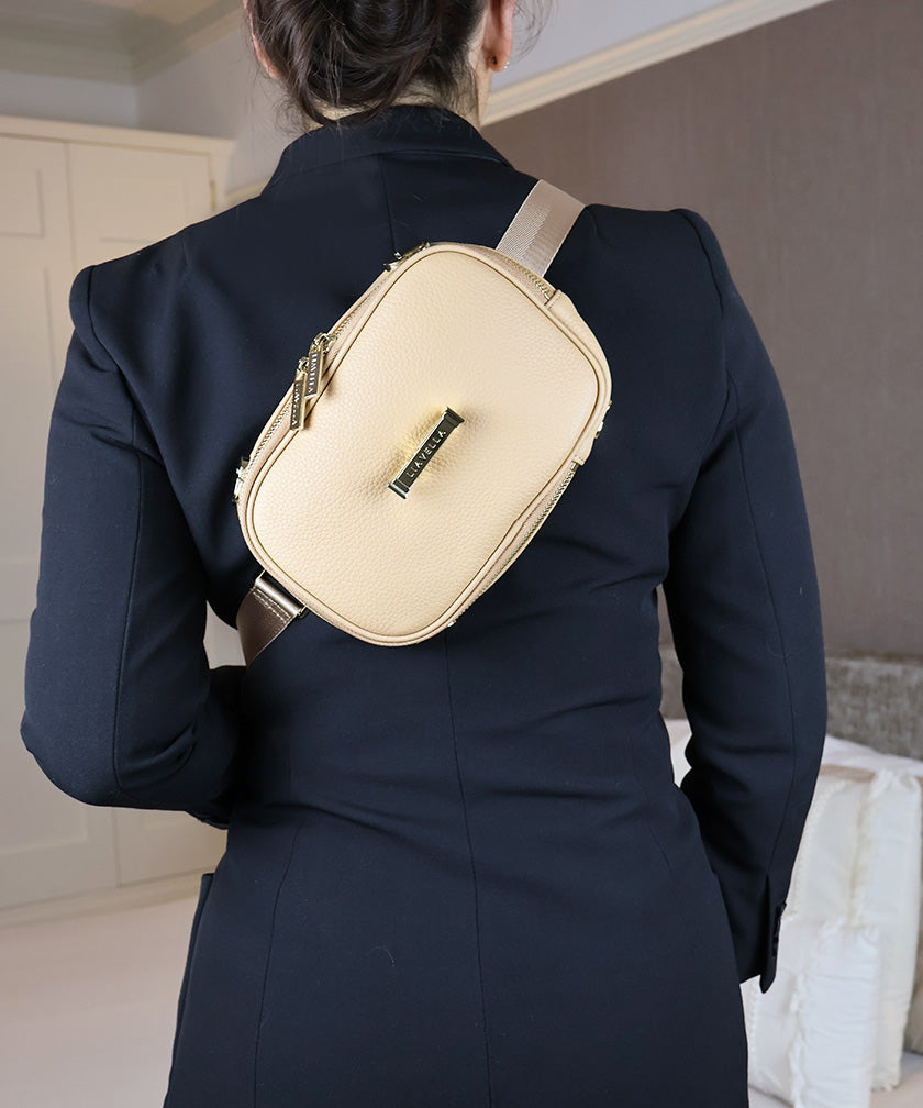 Person wearing the AVAIA Petit as a crossbody bag with a dark suit in an indoor setting.