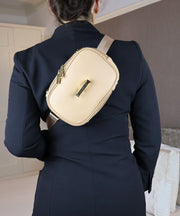 Person wearing the AVAIA Petit as a crossbody bag with a dark suit in an indoor setting.
