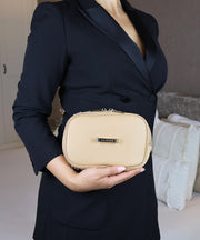 A woman in a dark blazer holding the AVAIA Petit as a clutch bag.