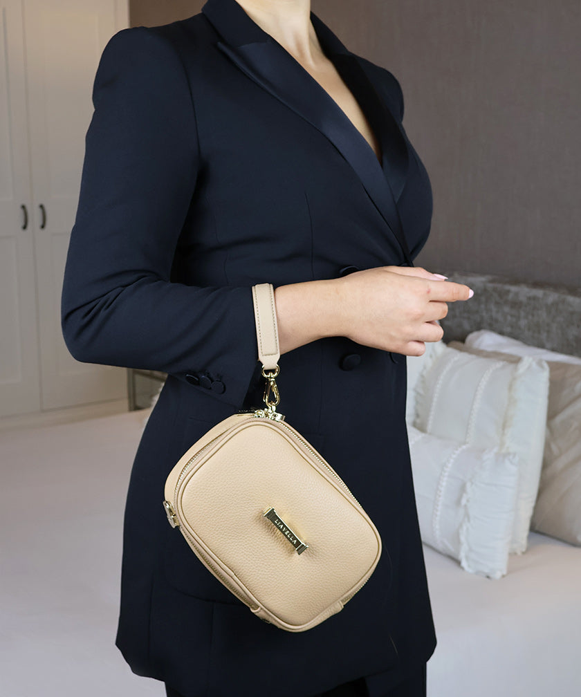 The AVAIA Petit bag worn with a handheld strap over the wrist in an indoor setting.