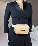Load image into Gallery viewer, Person wearing a navy blazer and the AVAIA Petit in creme caramel colour, in the bumbag style. They are in an indoor setting.
