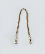 Load image into Gallery viewer, The Petit gold chain strap with gold hardware on a light gray background.
