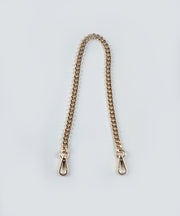 The Petit gold chain strap with gold hardware on a light gray background.
