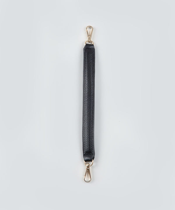 A short, black, handheld leather strap with gold hardware on a light gray background.