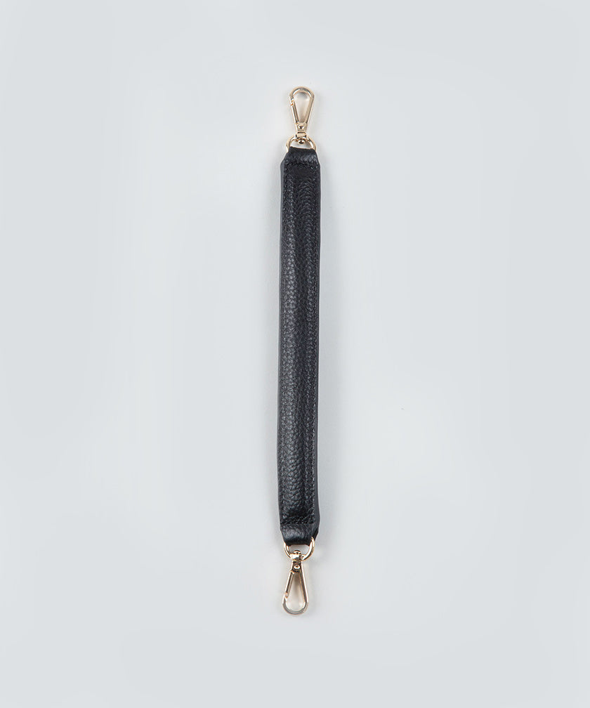 A short, black, handheld leather strap with gold hardware on a light gray background.