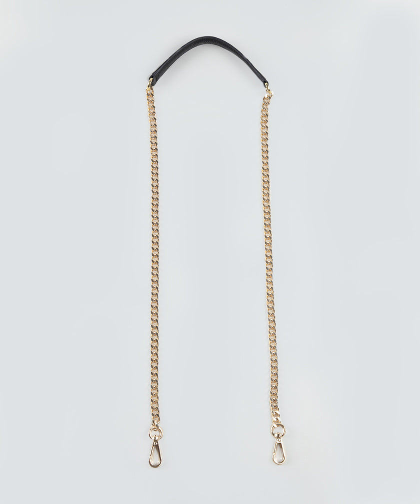 Gold chain strap with a black leather handle on a light gray background.