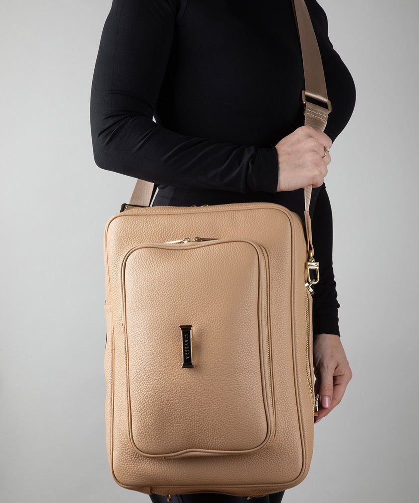 Crème caramel leather AVAIA bag held by a person against a gray background