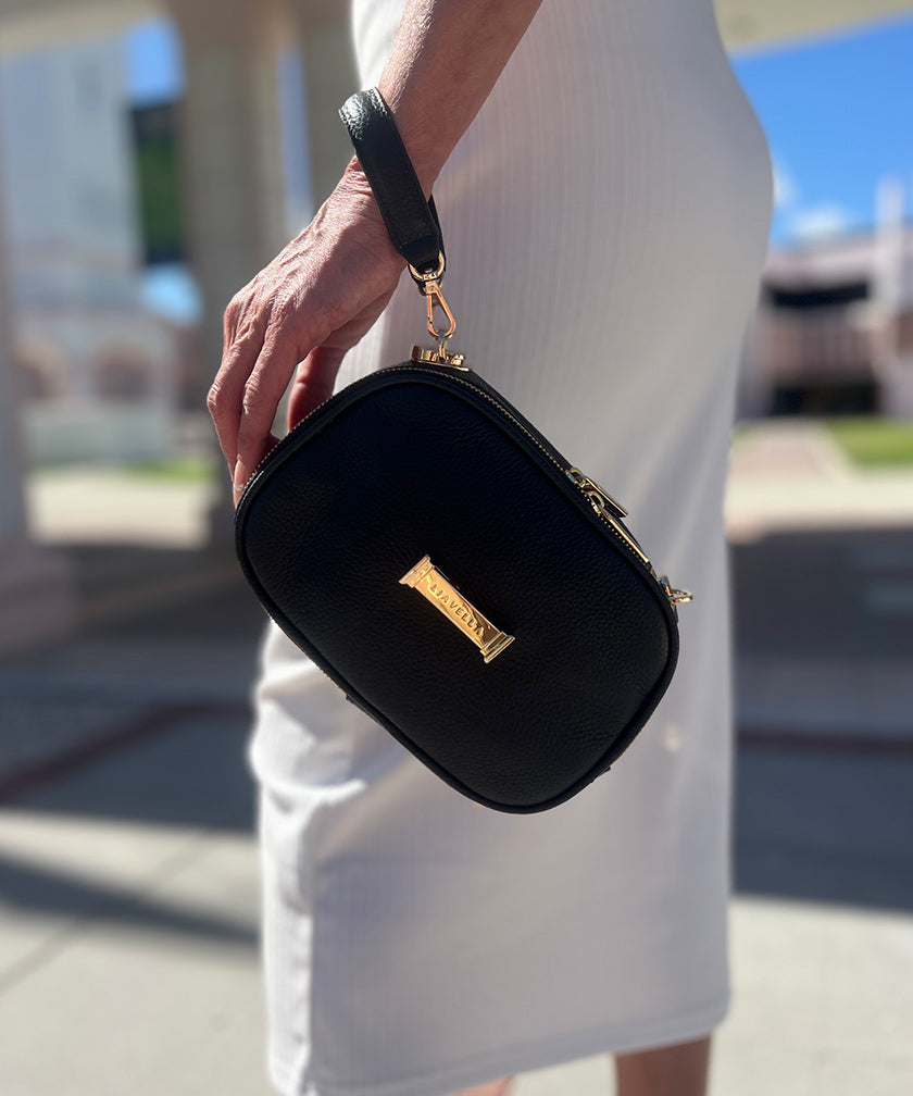 Person holding a AVAIA Petit noir around their wrist with gold accents outdoors