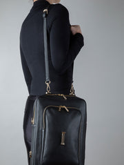 Person wearing a noir shoulder bag AVAIA bag with gold accents on a gray background
