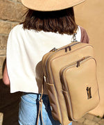 Load image into Gallery viewer, Person wearing a crème caramel AVAIA as a backpack with a wooden background