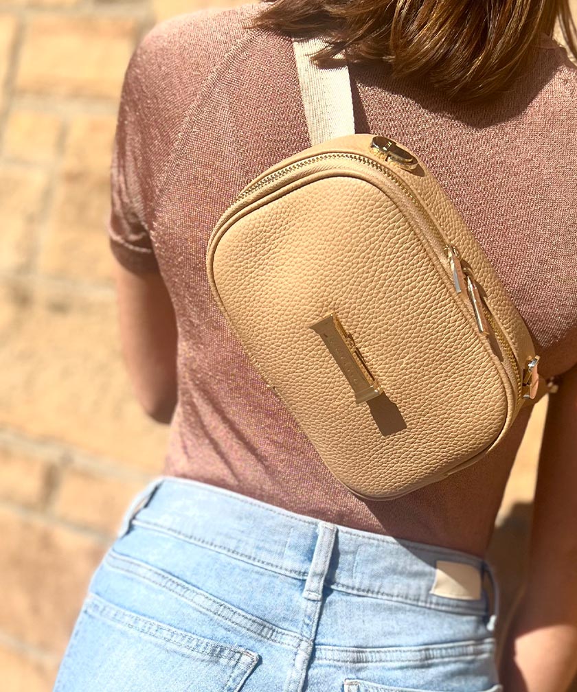 Person wearing a crème caramel AVAIA Petit as a crossbody bag with a blurred background